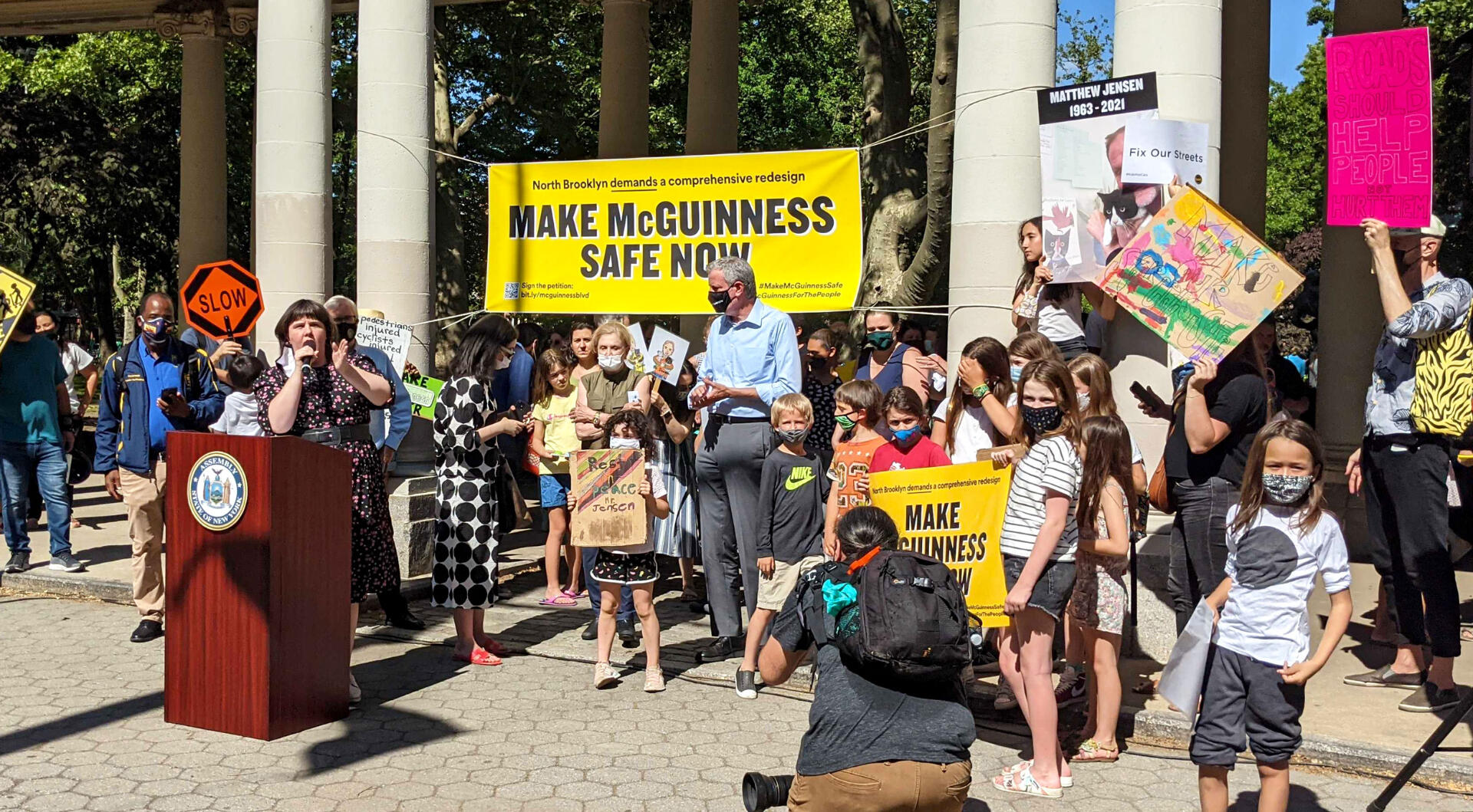 a woman speaks from a podium at a rally for safe streets investments on mcguiness boulevard