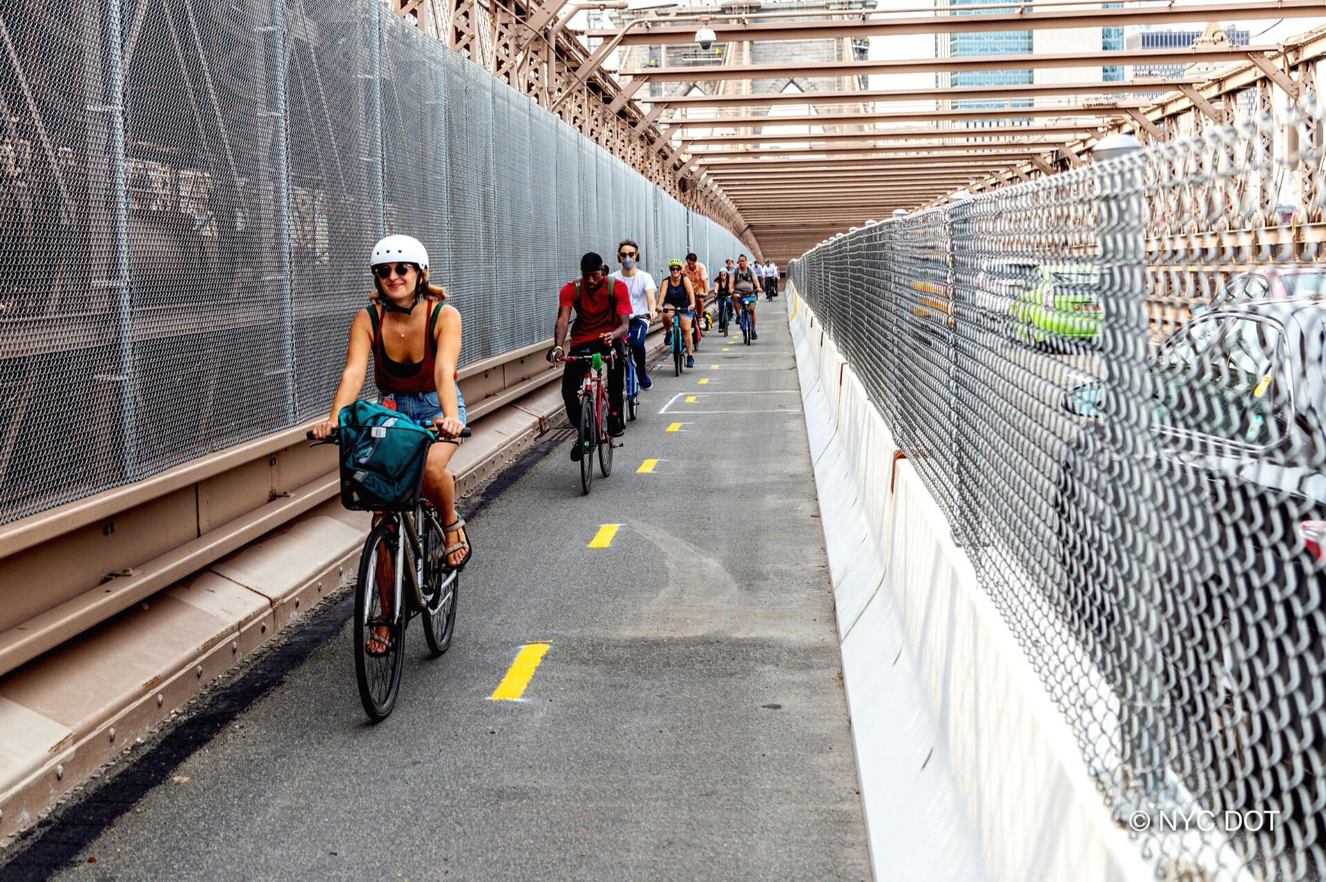 a line of cyclists bike across the brooklyn bridge in its protected bike lane